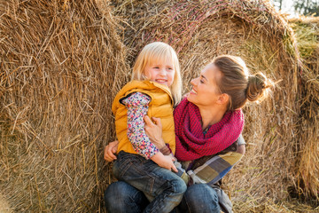 Wall Mural - Portrait of woman and happy child sitting on hay on farm