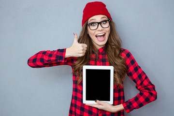 Woman showing blank tablet computer screen and thumb up