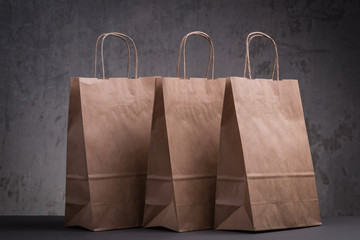 Three craft paper bags over the greyl background