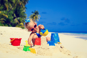 Wall Mural - cute little girl playing with sand on beach