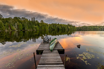 Wall Mural - Green Canoe and Chairs on a Dock at Sunset