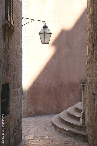 Fototapeta na wymiar Old street with lamp and stairs in Dubrovnik, Croatia. Dubrovnik is famous touristic location and UNESCO World Heritage Site. Natural light and interesting shadow. 