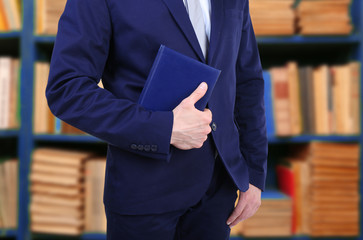 Poster - Male hand holding book on bookshelves background