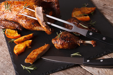 Cutting the roast duck close up on a slate board. Horizontal
