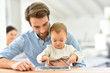 © goodluz - Man with baby looking at digital tablet