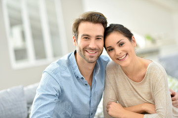 Wall Mural - Young smiling couple sitting in sofa at home