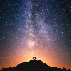 Wall Mural - universe for two. silhouettes of two people standing together holding hands against the milky way on