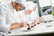 © W PRODUCTION - pastry cook professional team man and woman in restaurant kitchen preparing a chocolate dessert