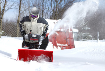 A man works snow blowing machine