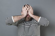 © STUDIO GRAND WEB - mistake concept - disturbed middle age man with striped sweater hiding his face for blindness expressing regret and disappointment