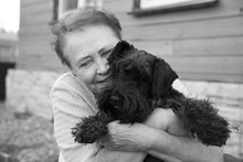 Portrait Of An Old Woman Holding Black Dog