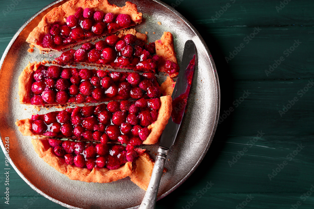 Tart with raspberries on tray, on wooden background