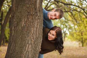 couple peeking out from behind a tree