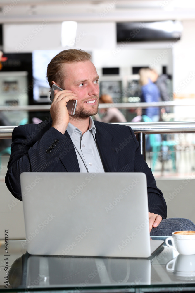 Young attractive businessman having lunch and working in a cafe