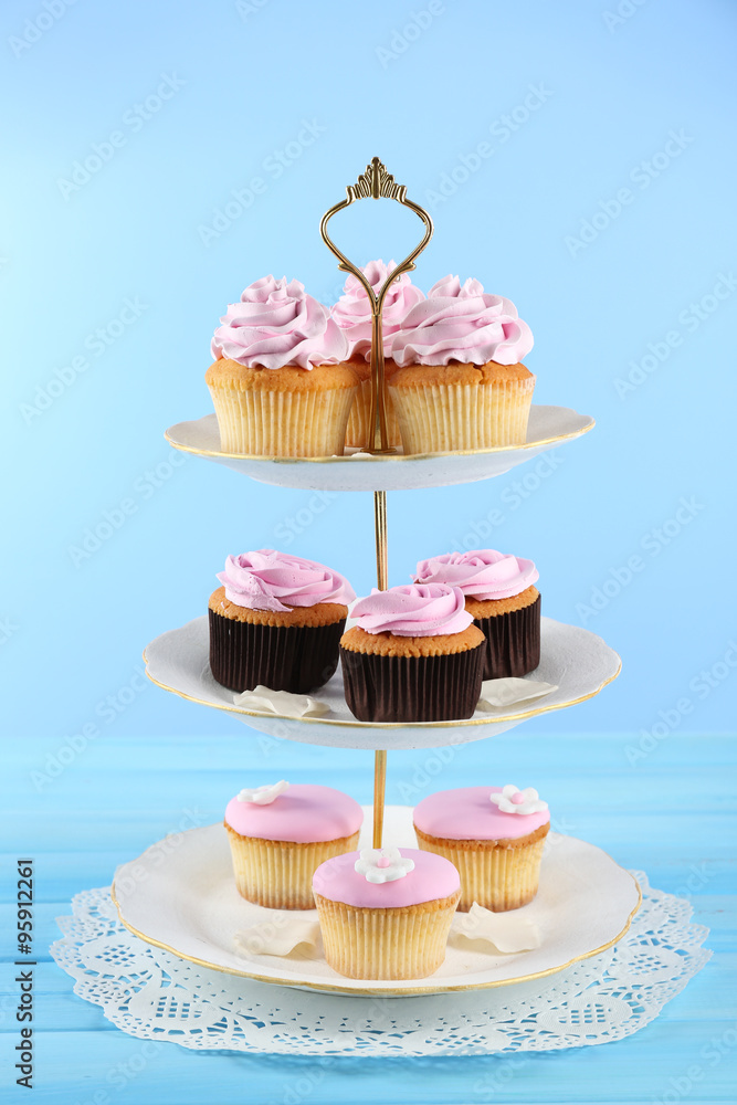 Tasty cupcakes on stand, on color background