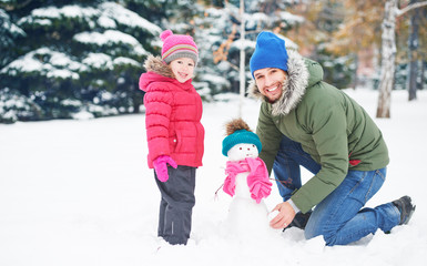 Canvas Print - Happy family father and child girl makes snowman in winter