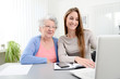 © W PRODUCTION - young woman helping an old senior woman doing paperwork and administrative procedures with laptop computer at home