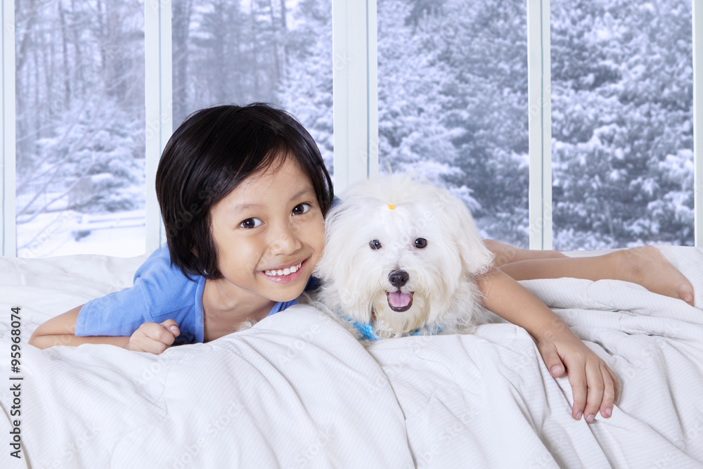 Little girl lying on bed with her puppy Stock Photo | Adobe Stock