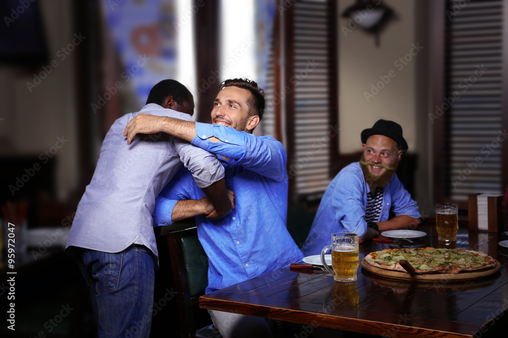 Young men drinking beer and talking in cafe