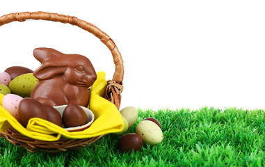 Wall Mural - Easter chocolate bunny and eggs on green grass, on white background