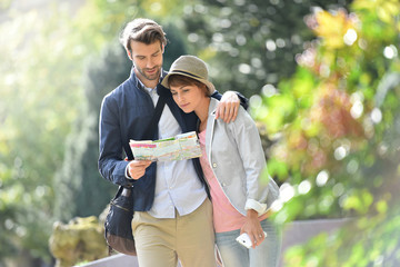 Wall Mural - Young couple walking in park and reading city map