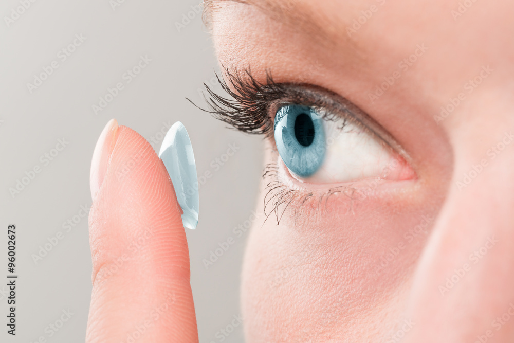 Woman inserting a contact lens in eye. - obrazy, fototapety, plakaty 