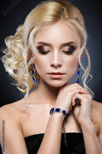 Poster Beautiful blond girl in a black dress with evening haircut form of waves and bright makeup