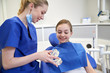 © Syda Productions - happy dentist showing jaw model to patient girl
