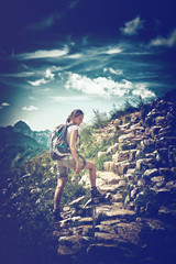 Wall Mural - young woman hiking on rocky mountainside trail
