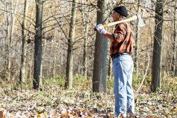 Poster - side view of senior lumberjack in nature holding an axe on his shoulder