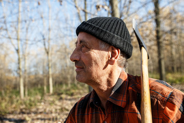 Poster - Portrait of senior lumberjack in nature holding an axe on his shoulder