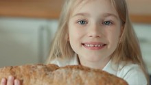 Girl Smelling A Bread And Looking At Camera