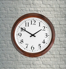 Wall clock with wooden frame on brick grey wall