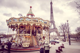 Fototapeta Miasto - Paris, France - March 18, 2012: Children accompanied by their parents and grandparents play the carousel of the Eiffel Tower in Paris on a wet and cloudy day in March