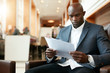 © Jacob Lund - Young african businessman at hotel lobby reading documents