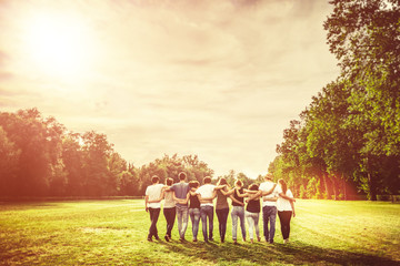 group of teenage friends in the park at sunset