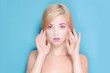 young woman blond hair on a blue background with pink makeup 