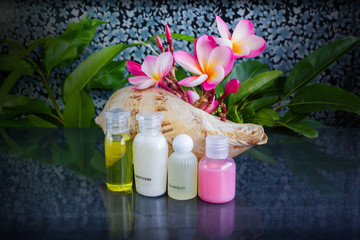 Wall Mural - Mini set of bubble bath and shower gel in sea conch shell  decorated with beautiful flower plumeria 