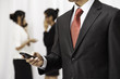 © psphotography - businessman using his mobile phone while two women are talking in the background