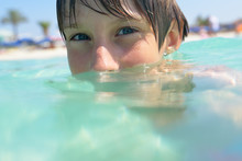 Little Boy Swimming In Sea With Clean Turquoise Water Transparen