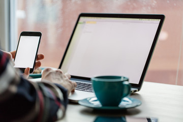 Man working on notebook, with a fresh cup of coffee and cell phone.