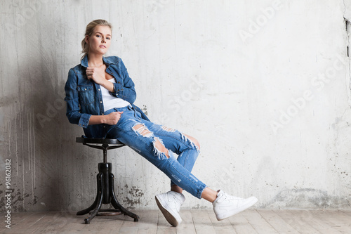 Femme en jeans assis sur une chaise en bois Tableau sur Toile