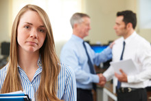 Unhappy Businesswoman With Male Colleague Being Congratulated