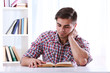 © Africa Studio - Young man reading book at table in room
