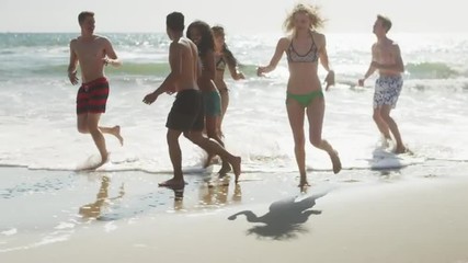 Wall Mural - Happy Group of multi ethnic friends running along beach shore