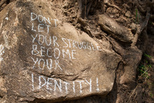 Don´t Let Your Struggle Become Your Identity. Creative Motivation Concept Written On A Rock.