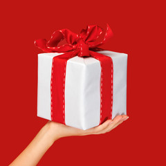 close up hand holding christmas gift box over red