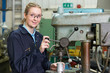 © highwaystarz - Female Apprentice Engineer Using Drill In Factory