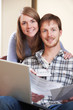 © highwaystarz - Happy Young Couple Looking At Finances On Laptop