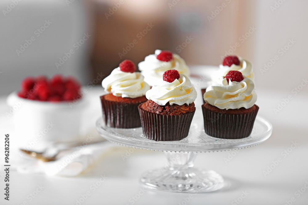 Beautiful chocolate cupcakes with cream and raspberry on table